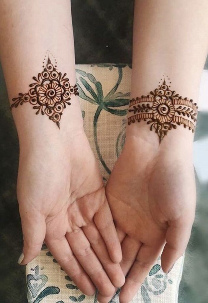 Bracelet style floral mehndi design on wrist featuring delicate flower motifs arranged like jewelry, fine vine detailing, elegant minimalist henna pattern on female hand in modern 2026 aesthetic style.