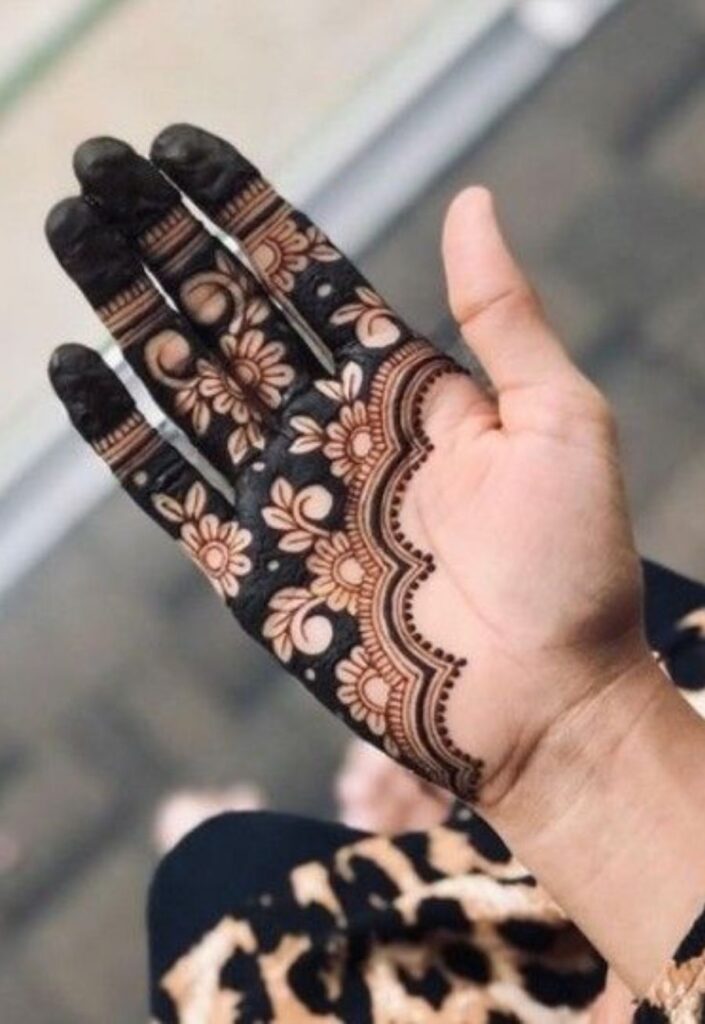 Half-hand floral mehndi design with one side fully covered in intricate flower motifs and vines, balanced negative space on the other side, elegant modern 2026 henna style on female hand.
