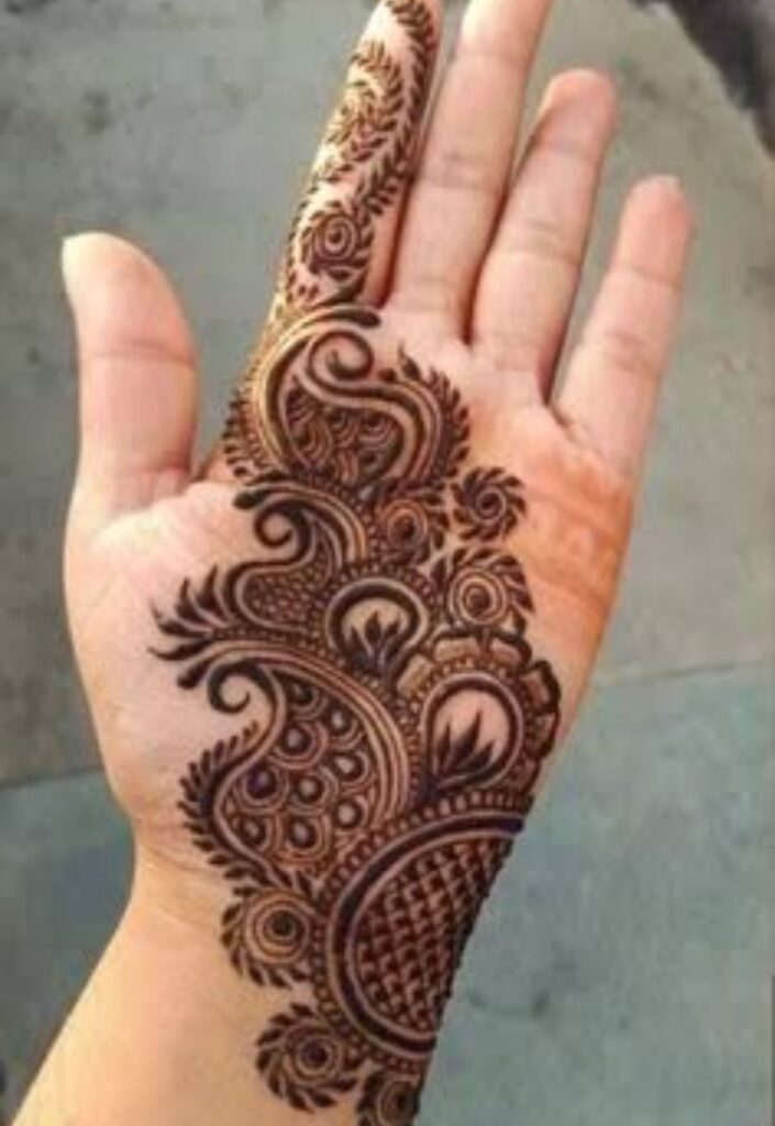 Paisley and floral mix mehndi design combining traditional paisley shapes with delicate flower motifs and fine vine detailing, balanced intricate henna pattern on female hand in elegant 2026 style.