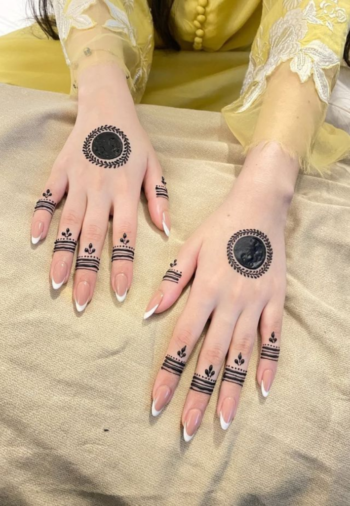 Close-up view of a simple circular mehndi design on the palm featuring a clean mandala-style center circle with minimal detailing and soft floral accents around it.