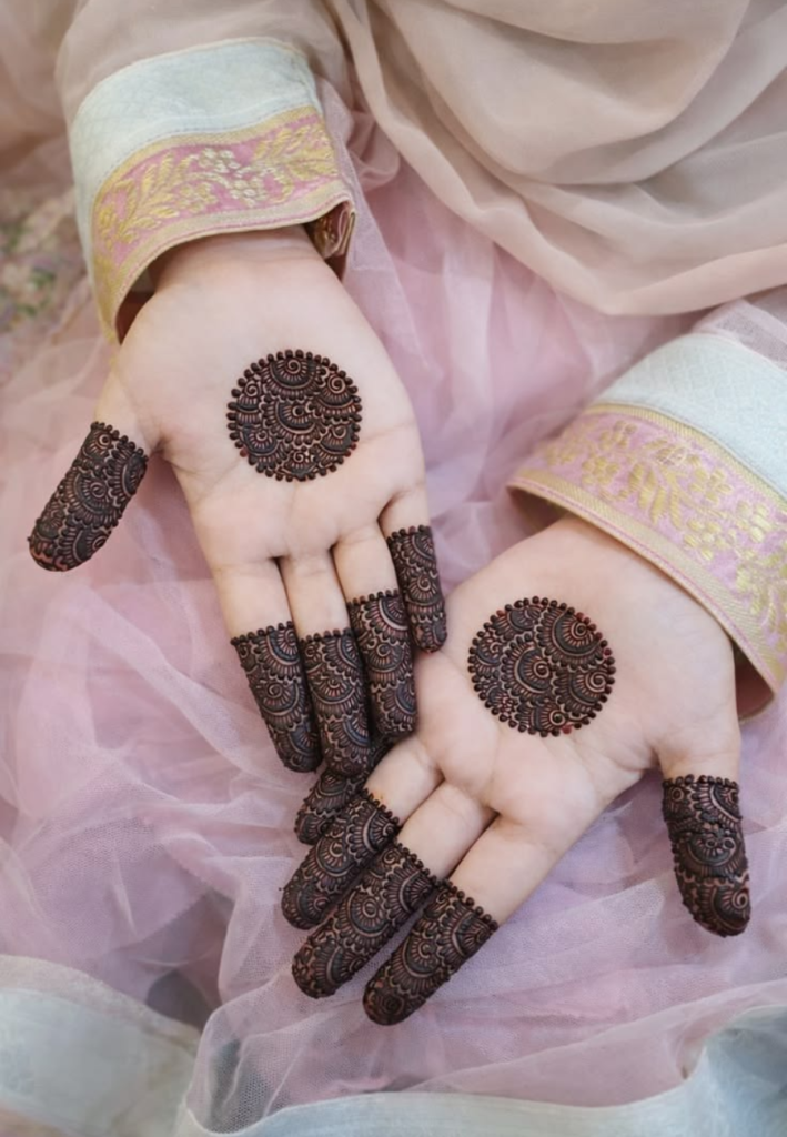 Close-up view of a beautiful circular mandala-style mehndi design featuring intricate floral and geometric patterns on a hand.