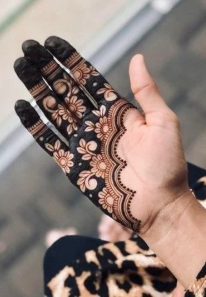 Floral half hand mehndi designs 2026 featuring detailed rose and petal patterns with delicate leafy vines applied from fingers to mid-hand, creating an elegant and feminine henna look with soft spacing.