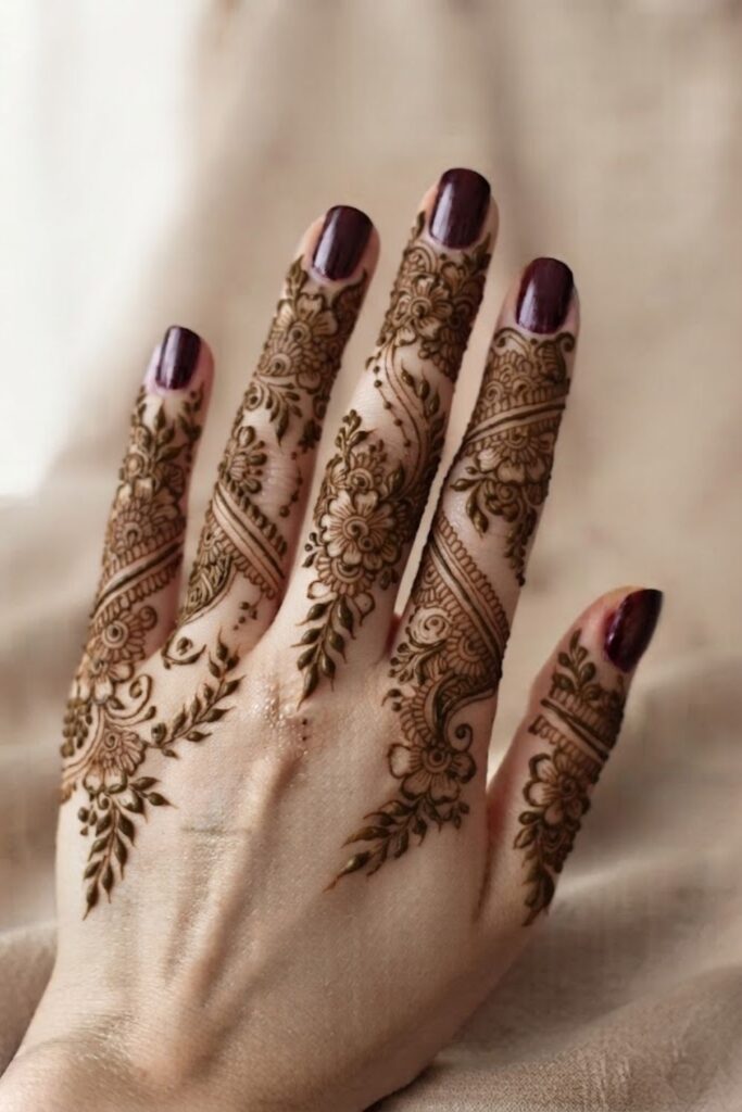 Full finger henna design with intricate floral details, leafy vines, and delicate patterns