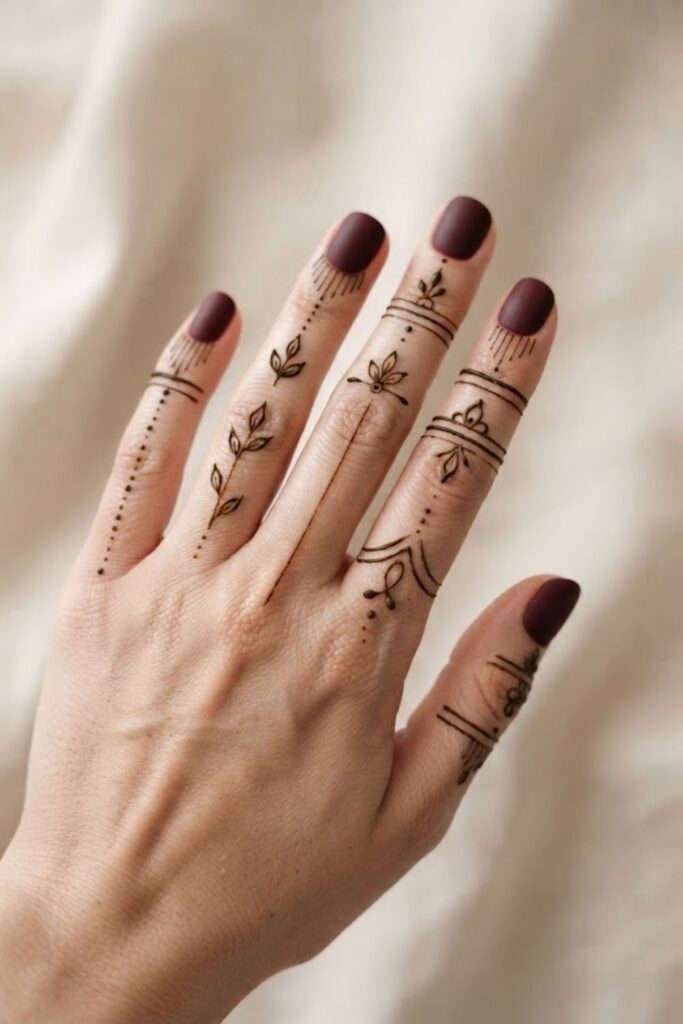 Modern minimal finger mehndi design with delicate leaves, dots, curves, and fine henna lines